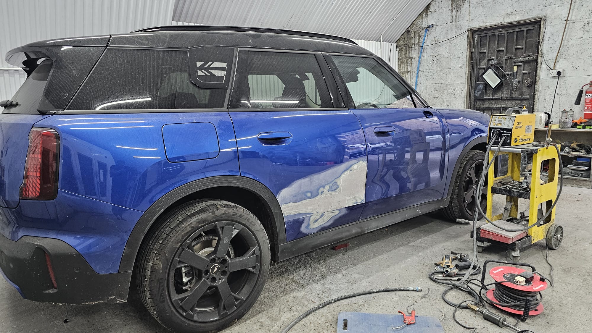 Blue KGM SUV with side-panel damage prepared for repair at Autophix
