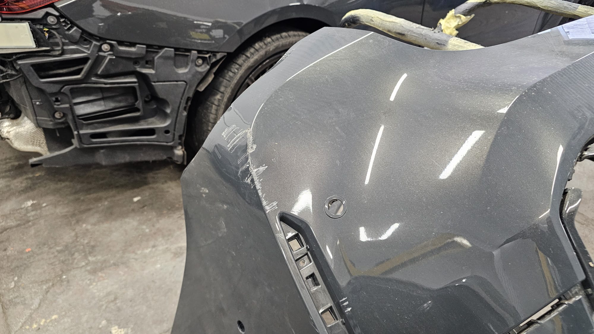 BMW M4 rear bumper with visible surface damage before repair