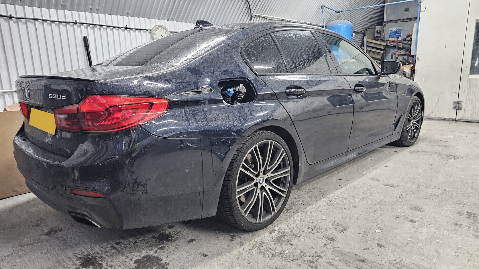 Dark BMW 530d with rear-quarter damage before repair